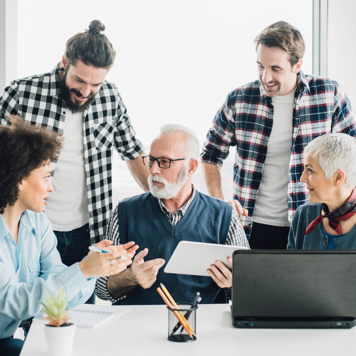 Eine Familie aus verschiedenen Generationen sitzt zusammen an einem Tisch, diskutiert und plant gemeinsam, symbolisiert eine Familie, die den Erbfall regelt