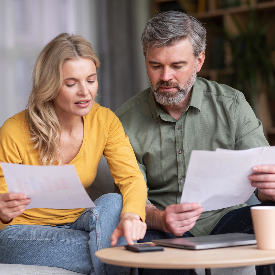 Ein älteres Paar sitzt auf einem Sofa und überprüft gemeinsam Dokumente, symbolisiert eine Familie, die ihre Vorsorge regelt